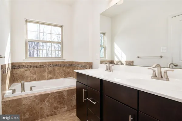 a bathroom with a bathtub sink double vanity and mirror