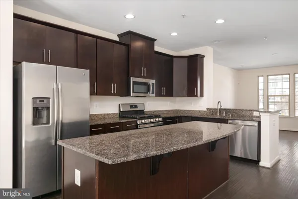 a kitchen with stainless steel appliances kitchen island granite countertop a refrigerator and a stove top oven