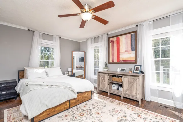 a bedroom with a bed next to a window with a workspace