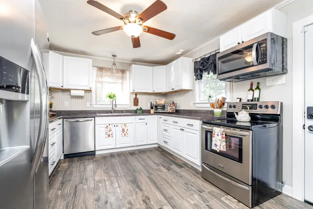 a kitchen with stainless steel appliances granite countertop a stove a sink and white cabinets
