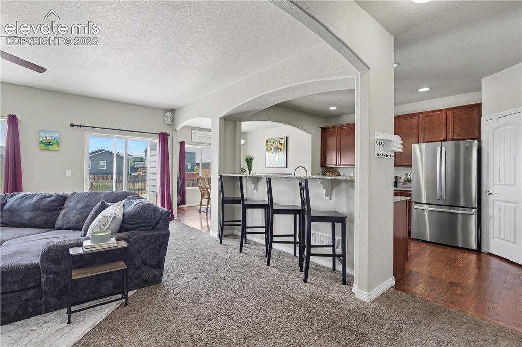 6598 Alliance Loop Colorado Springs, CO 80925 - Photo 4 of 39 Open-concept living space featuring a carpeted area, arched entryway, and sliding glass doors