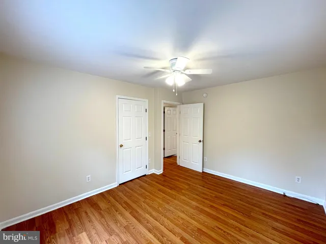 an empty room with wooden floor and fan