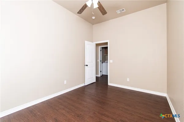an empty room with wooden floor and a ceiling fan