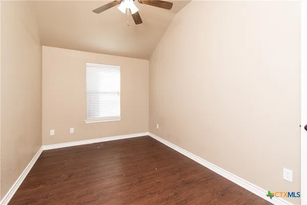 an empty room with wooden floor chandelier fan and windows