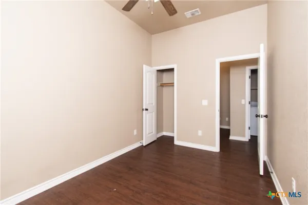 an empty room with wooden floor and a ceiling fan
