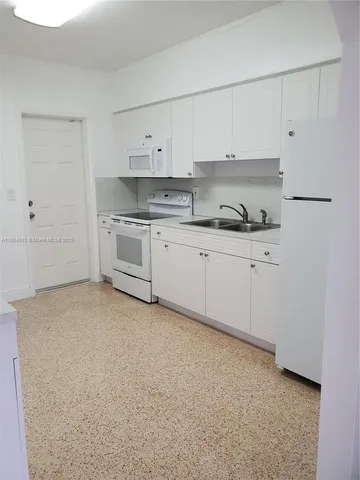 a kitchen with granite countertop white cabinets and white appliances