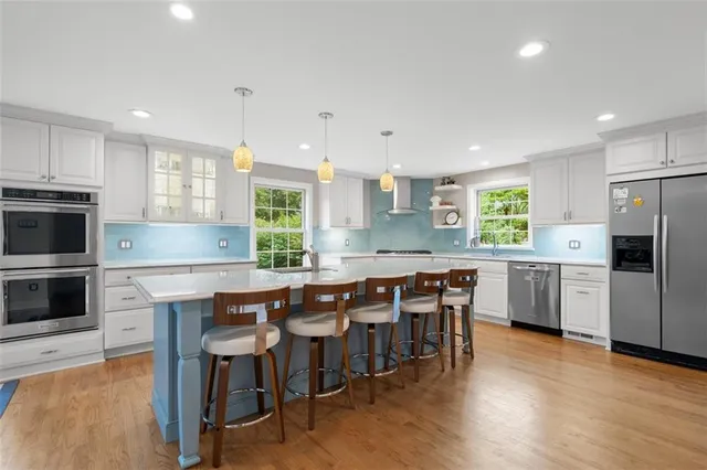 a kitchen with stainless steel appliances wooden floors and white cabinets