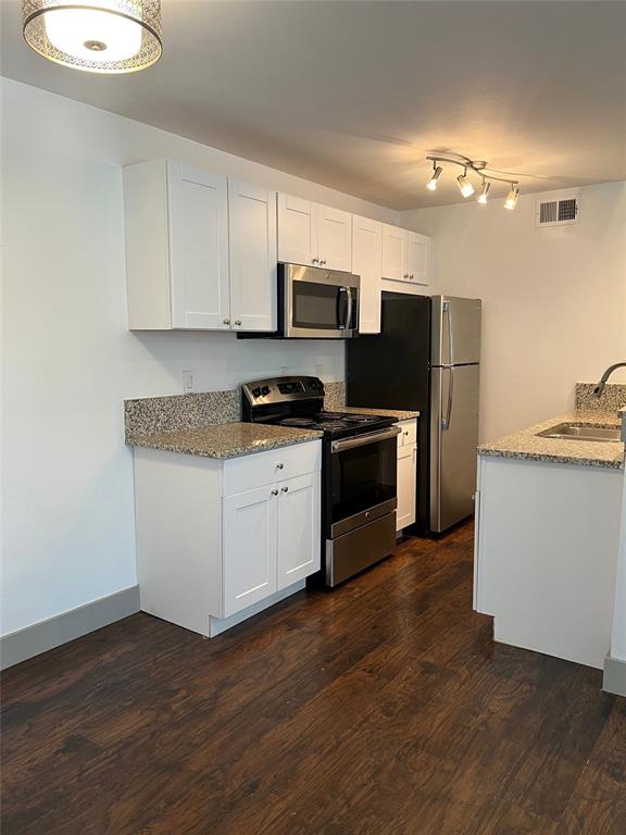 4633 Fairmount Street, Unit 213 Dallas, TX 75219 - Photo 3 of 9 Kitchen featuring stainless steel appliances, white cabinets, light stone counters, and dark wood-type flooring