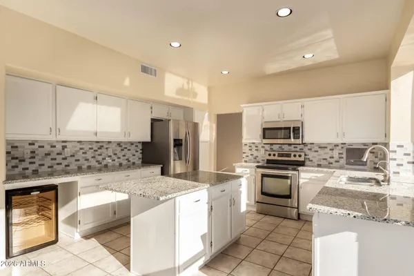 a kitchen with stainless steel appliances kitchen island granite countertop a sink stove and refrigerator