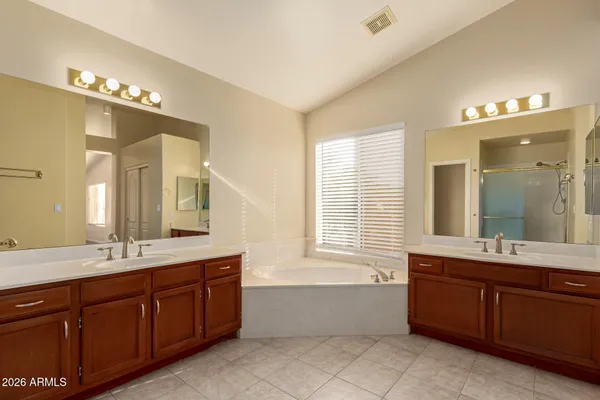 a spacious bathroom with a tub double sink and mirror