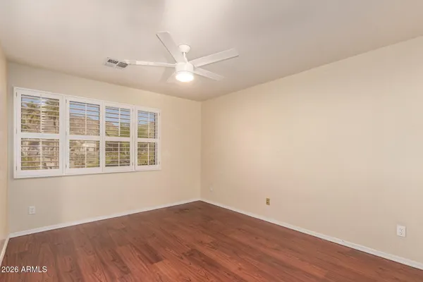 a view of empty room with wooden floor and fan