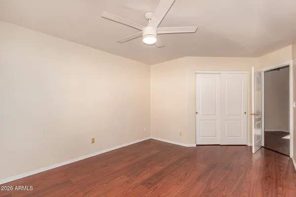 an empty room with wooden floor and a ceiling fan