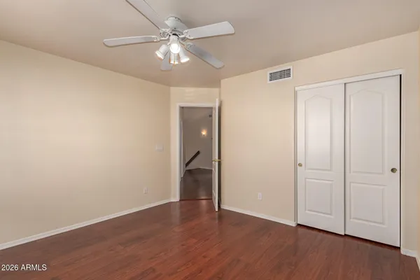 an empty room with wooden floor and a ceiling fan