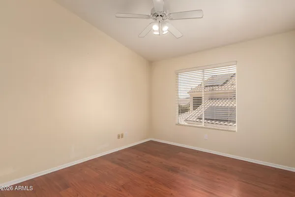 an empty room with wooden floor fan and windows