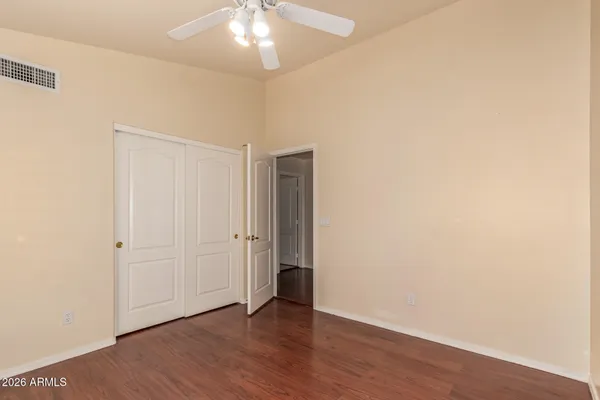 an empty room with wooden floor and chandelier fan