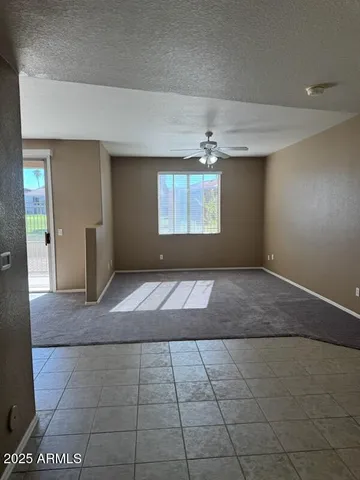 an empty room with kitchen and chandelier fan