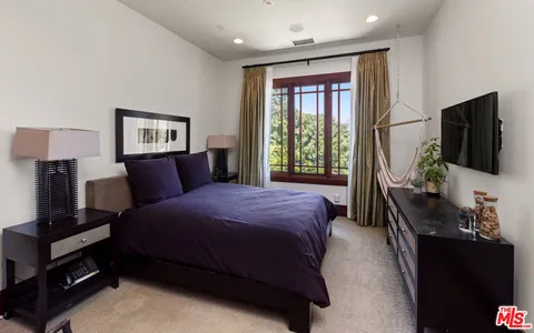 a bedroom with a bed and a flat tv screen on a dresser