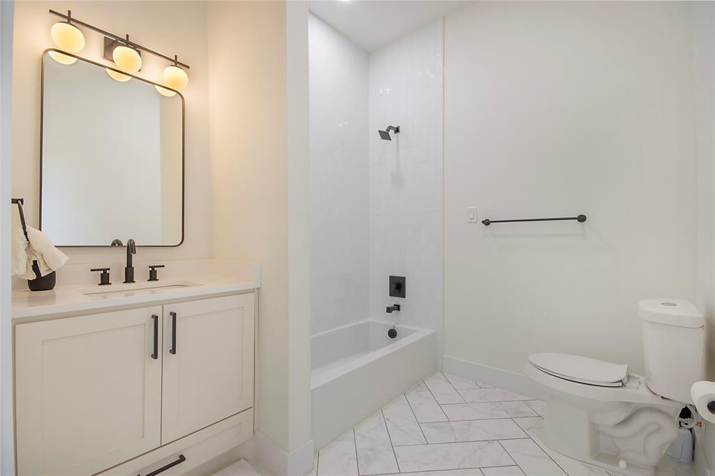 4648 Corregidor Street Dallas, TX 75216 - Photo 25 of 30 a bathroom with a toilet a sink a mirror a bathtub and vanity