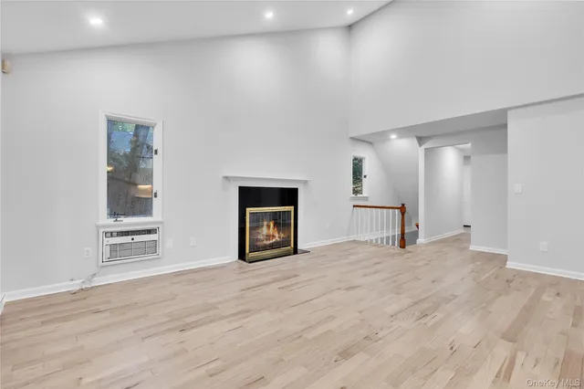 a view of an empty room with wooden floor and a fireplace