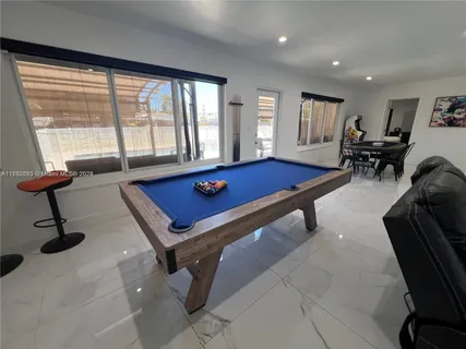 a living room with furniture pool table and floor to ceiling window