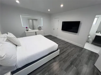 a bedroom with a bed a tv and wooden floor