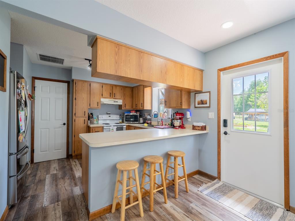 4381 Northeast 105th Place Anthony, FL 32617 - Photo 12 of 49 a kitchen with stainless steel appliances granite countertop a stove a refrigerator a sink a dining table and chairs with wooden floor