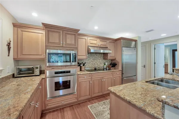 a kitchen with stainless steel appliances granite countertop a stove a sink and a refrigerator