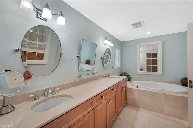 a spacious bathroom with a granite countertop double vanity sink a mirror and a bathtub