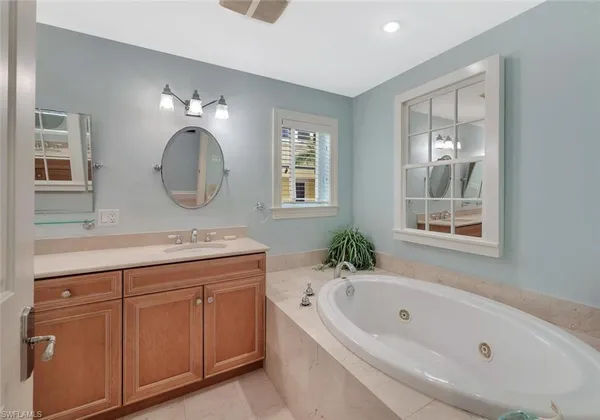 a bathroom with a tub a sink and a mirror