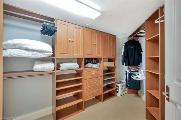 a view of walk in closet with clothes and shoes