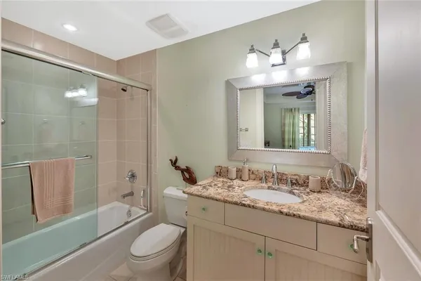 a bathroom with a granite countertop sink toilet a large mirror a bathtub and shower