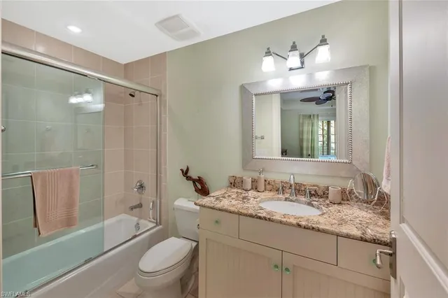 a bathroom with a granite countertop sink toilet a large mirror a bathtub and shower
