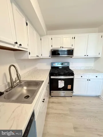 a kitchen with granite countertop a stove and white cabinets