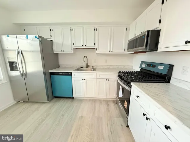 a kitchen with stainless steel appliances a stove a sink a refrigerator a microwave and cabinets