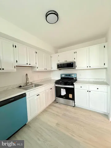 a kitchen with granite countertop a sink cabinets stainless steel appliances and a counter space