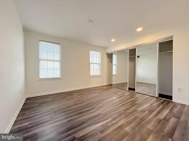 a view of an empty room with wooden floor and window