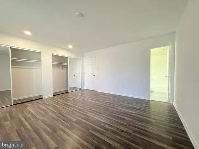 a view of an empty room with wooden floor and closet