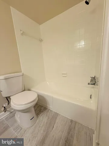 a white toilet sitting next to a bath tub and a shower