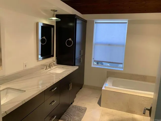 a bathroom with a granite countertop bathtub sink and mirror