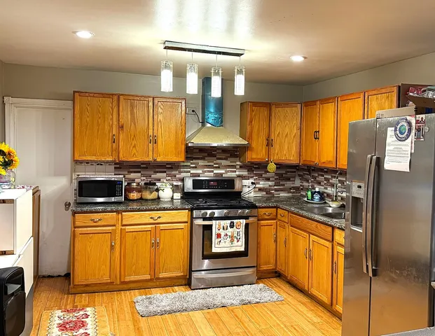 a kitchen with stainless steel appliances granite countertop sink stove and refrigerator
