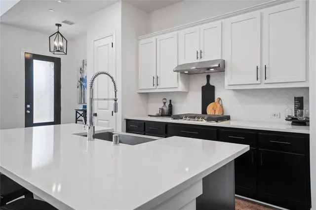 a kitchen with kitchen island granite countertop a sink a stove and cabinets