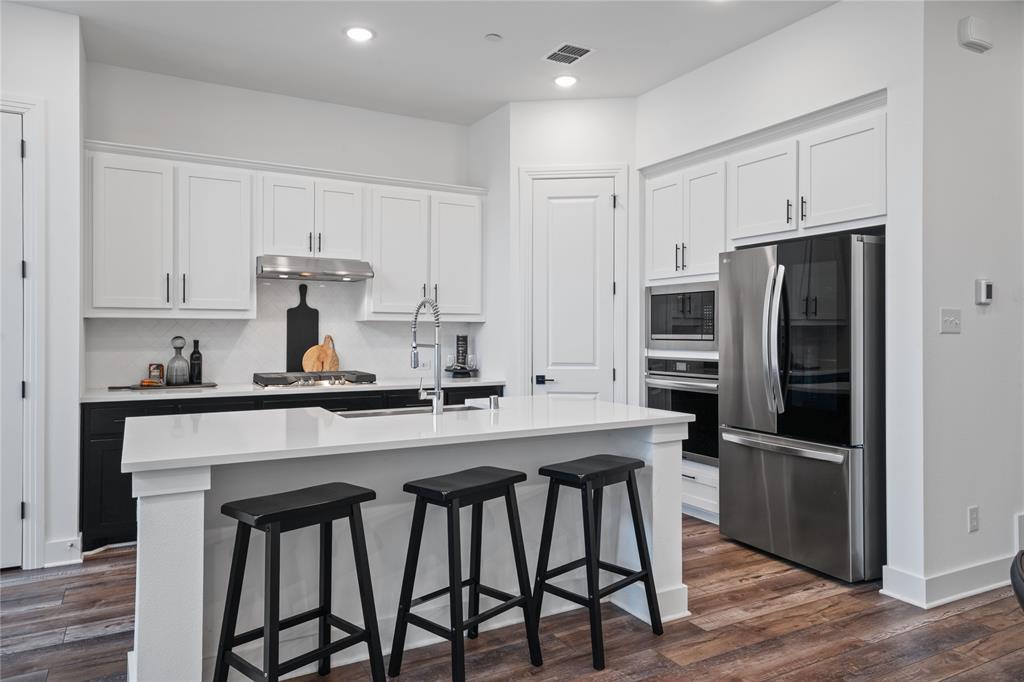 313 Sugar Maple Lane McKinney, TX 75071 - Photo 16 of 40 a kitchen with stainless steel appliances a sink a stove a refrigerator cabinets and wooden floor