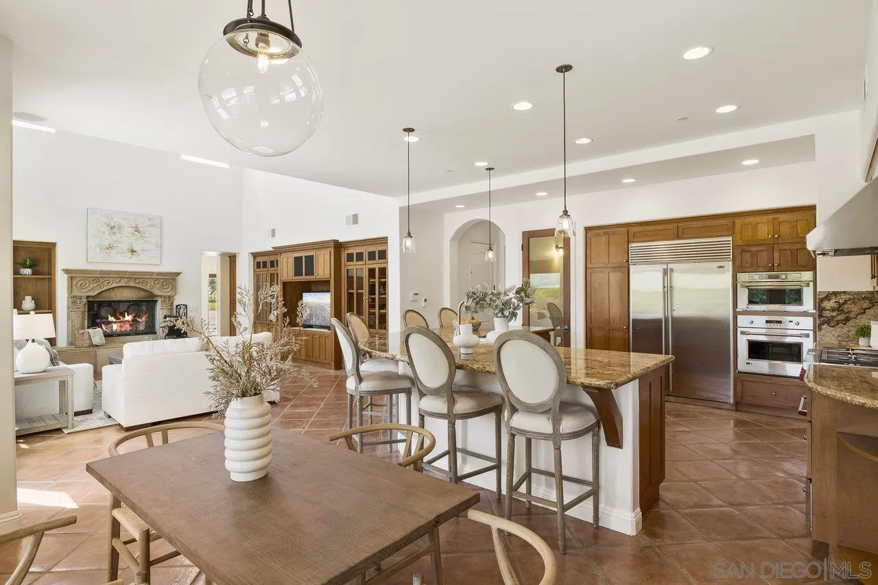 20919 Questhaven Road San Marcos, CA 92078 - Photo 18 of 54 a dining room with stainless steel appliances kitchen island granite countertop a table chairs and a refrigerator