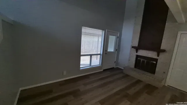 a view of a hallway with wooden floor and a bathroom
