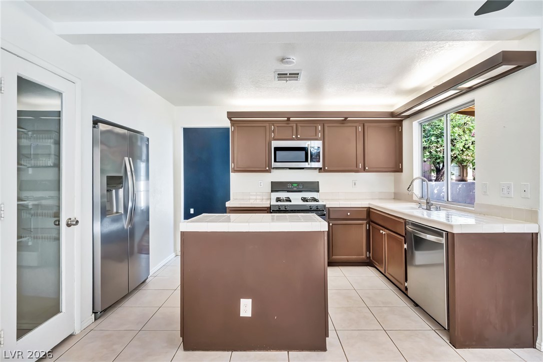 1402 Rim Fire Circle Henderson, NV 89014 - Photo 13 of 48 Tiled flooring and a functional central island anchor this open-concept culinary space.