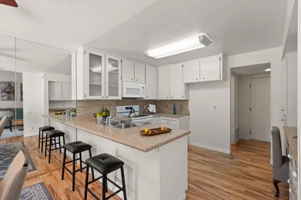 a kitchen with stainless steel appliances granite countertop a stove a sink dishwasher and white cabinets with wooden floor