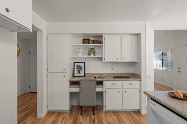 a kitchen with a white cabinets and wooden floor