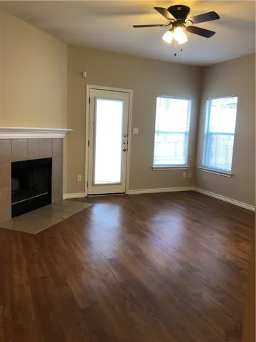 an empty room with wooden floor fireplace and windows