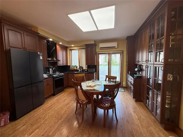 a kitchen with stainless steel appliances a dining table chairs refrigerator and cabinets