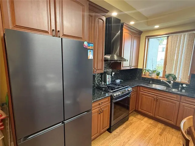 a kitchen with stainless steel appliances granite countertop a refrigerator a sink a stove and cabinets